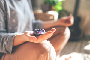 Woman meditating with amethyst crystal for spiritual energy and healing