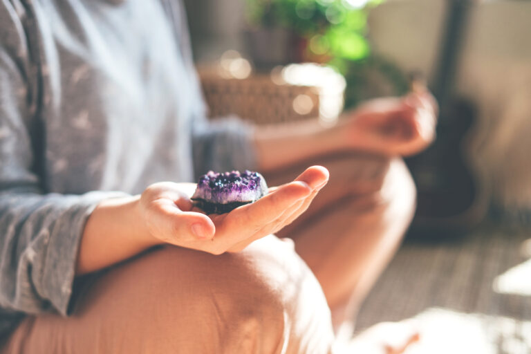 Woman meditating with amethyst crystal for spiritual energy and healing