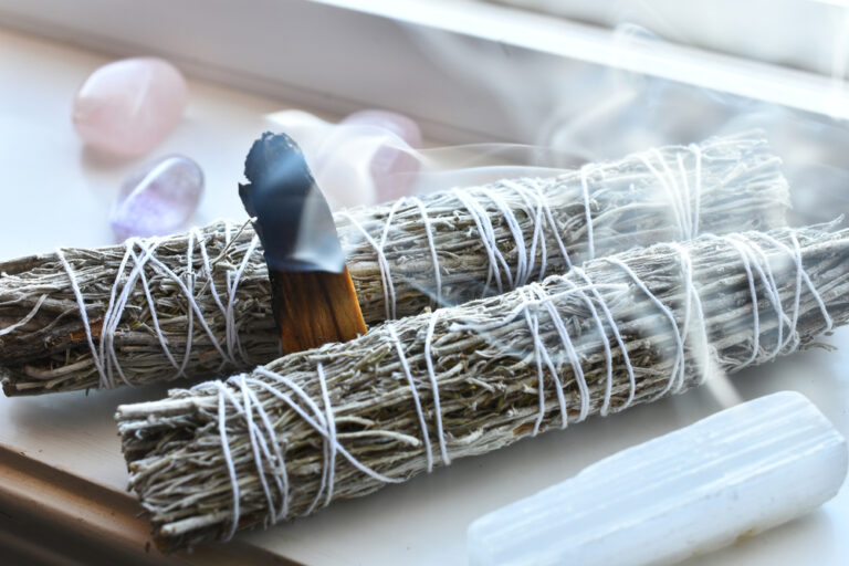 Smoldering sage smudge stick with Palo Santo and healing crystals