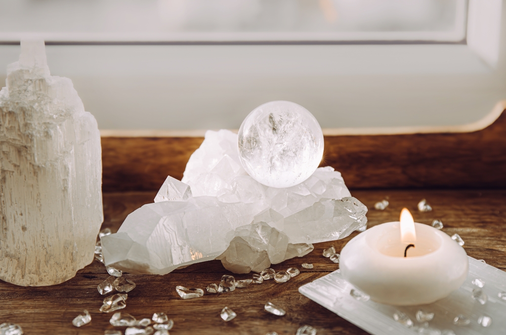 White selenite tower and clear quartz crystals with a candle for energetic cleansing