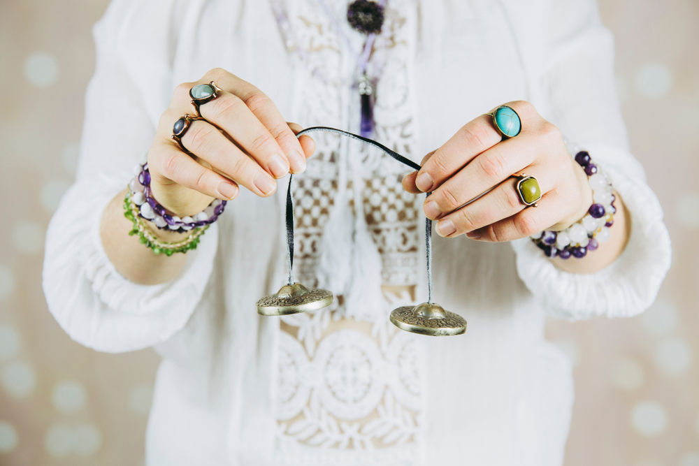 Hands holding Tibetan Tingsha bells used for sound cleansing and meditation rituals