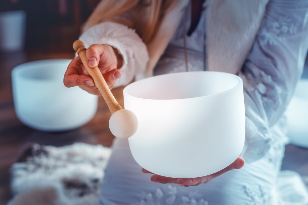 Woman playing a crystal singing bowl for energy cleansing and sound healing