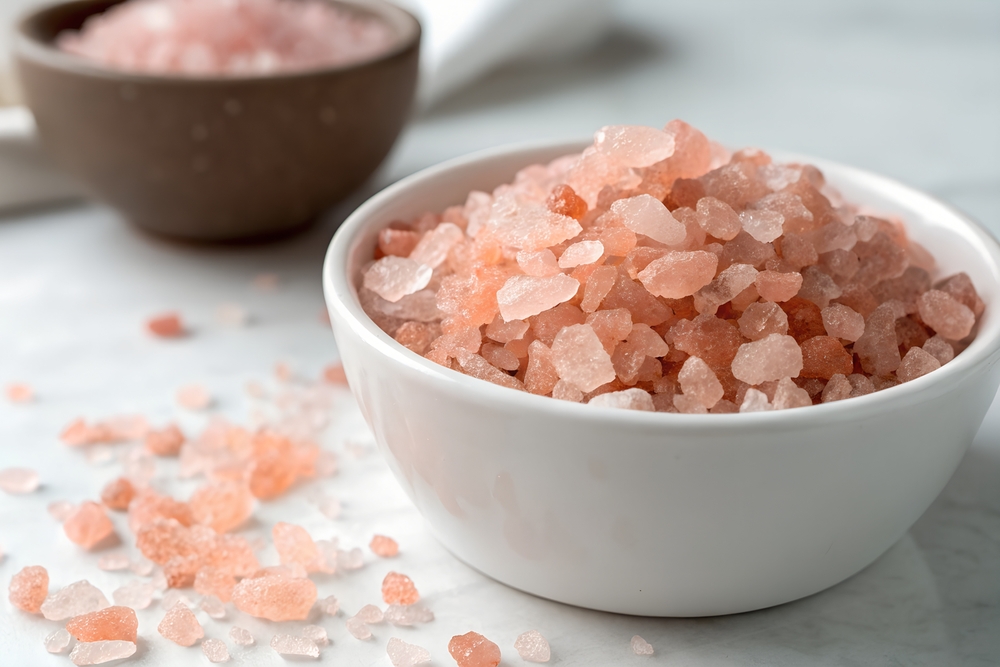 Pink Himalayan salt crystals in a white ceramic bowl, used for energetically cleansing gemstones